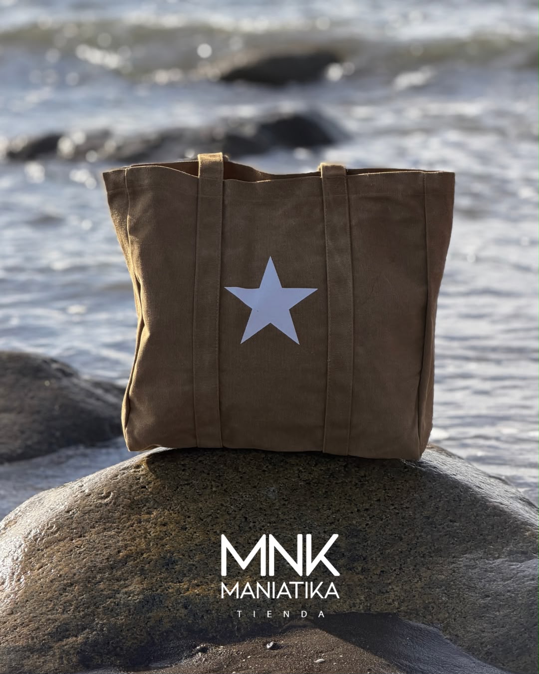 Bolso Estrella en color café, con la estrella blanca al frente, apoyado sobre una roca con el mar de Matanzas detrás.